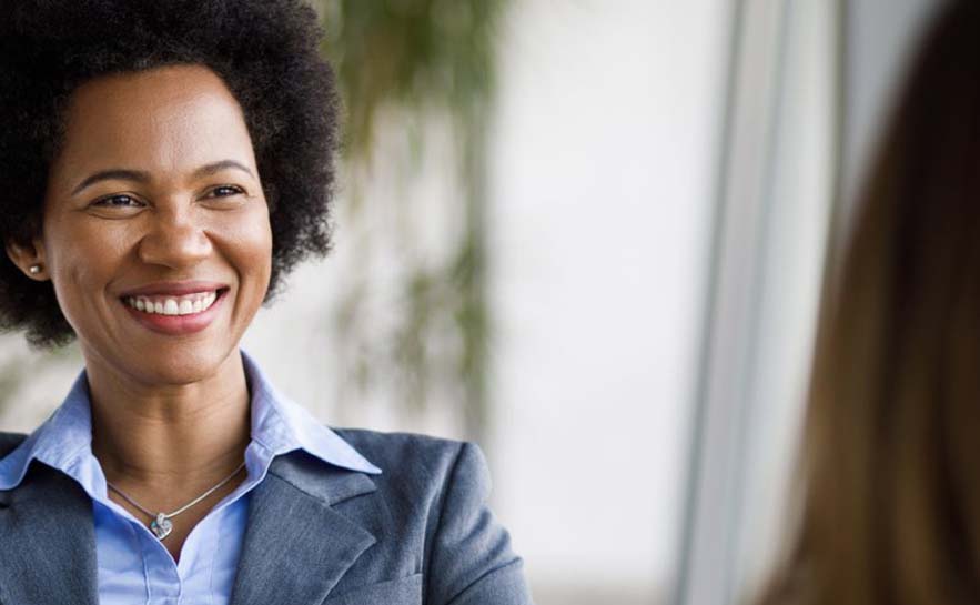 Smiling businesswoman in a suit having a conversation in a bright office setting.