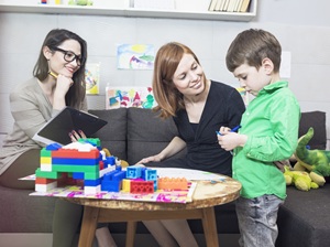 female counselor supervising a mom and her son while they play together with blocks at a table