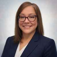 Vicki Copeland Headshot in  dark blazer white blouse and glasses