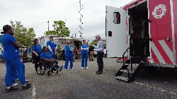 Disaster relief workers at back of ambulance in parking lot