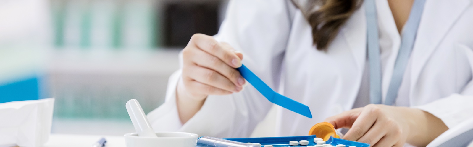 woman in white medical coat measuring medications in a pharamacy