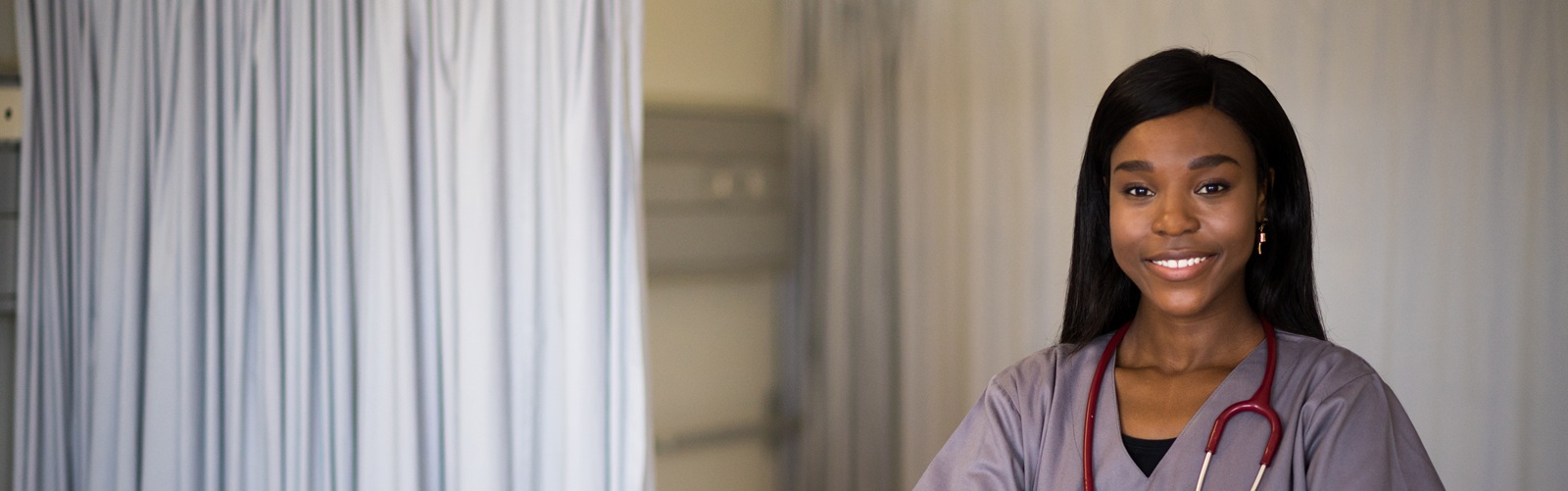young african american woman in purple scrubs standing in a hospital room