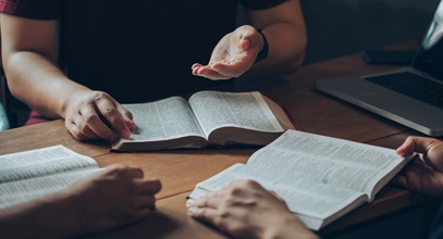 three people gathered around a table discussing theology