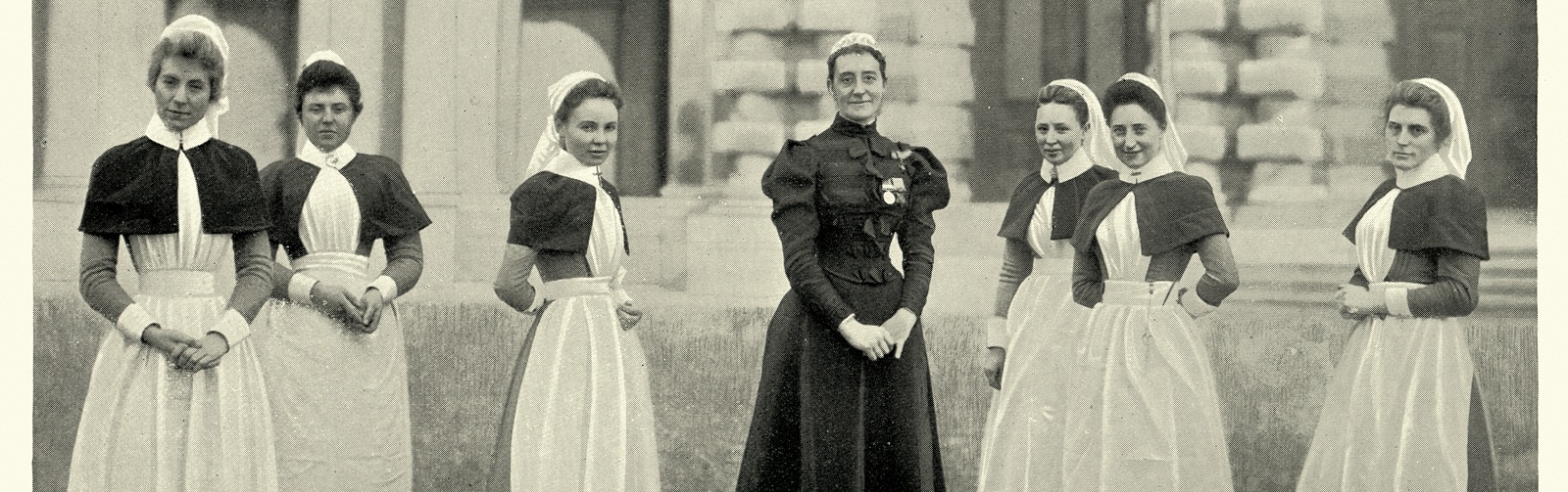 seven nurses from the early 1900s in their traditional uniforms of the time