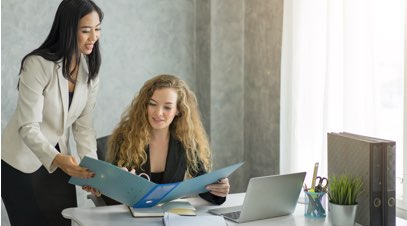 2 Female business professionals reviewing information in folder at desk-alt-text