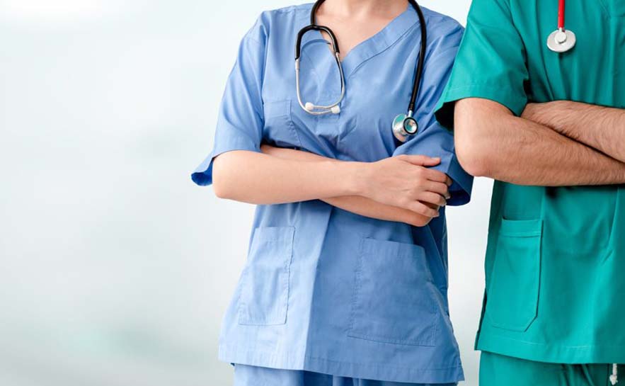 Two healthcare professionals standing side by side with arms crossed, both wearing scrubs and wearing a stethoscope around their necks.