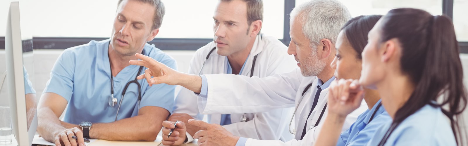 Team of nurses and doctor discussing information on a computer