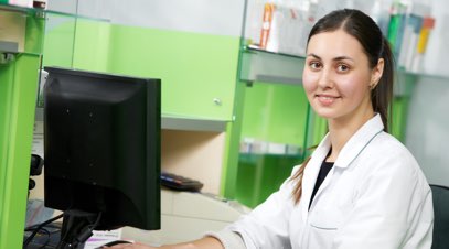 Female nurse in front of computer smiling-alt-text