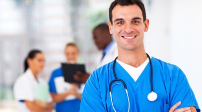 Male nurse smiling in front of team of medical professionals-alt-text
