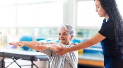 Physical therapist holding older patient's arms outstretched-alt-text