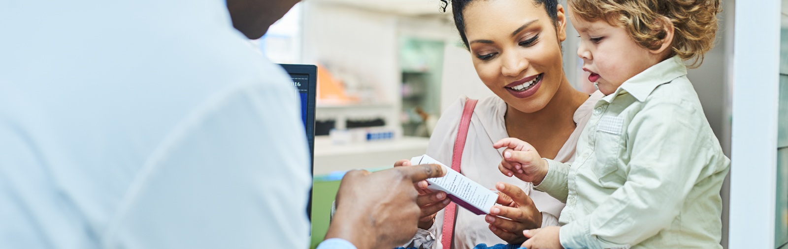 pharmacist helping a woman choose a medicine with her small child nearby