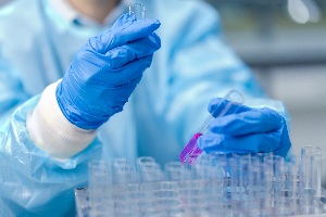 person in medical safety scrubs looking at test tubes