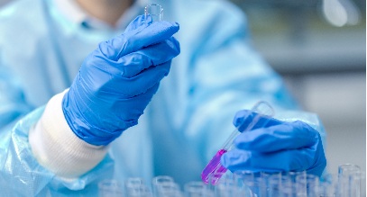 person in medical safety scrubs looking at test tubes