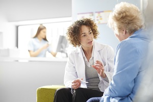 pharmacist in a white coat speaking with an older female patient in a blue coat in a hospital