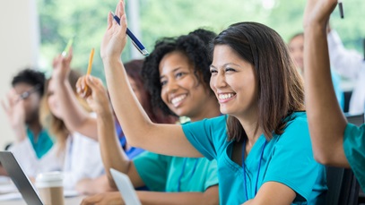 Group of nursing student raising their hands while they sit in a classroom 
